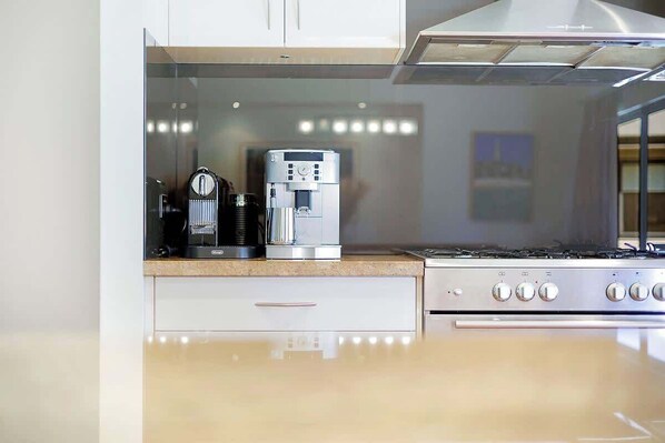 Une cuisine équipée d’une machine à café, d’une cuisinière et d’un meuble blanc.