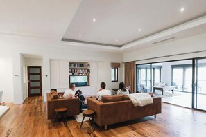 A modern living room with a sofa set, a television, and a bookshelf. - Redgum Treehouse - Luxury home in wine country! (Western Australia)