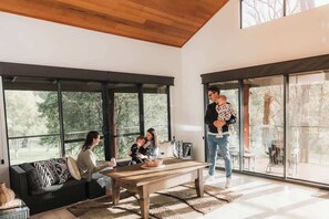 Un intérieur moderne avec de grandes fenêtres, un plafond en bois, un canapé et une table.