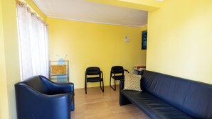 A living room with a blue sofa, two black chairs, and a yellow wall. - Falledge Apartments - Pebble (St George)