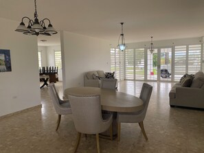 A spacious living area with a dining table and chairs, a sofa, and a chandelier.