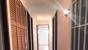 Un pasillo con suelo de baldosas, puertas de madera y un acceso de vidrio.