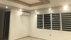 Una habitación con ventana de listones, techo empotrado y aire acondicionado.