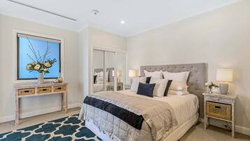 A bedroom with a large bed, a bedside table with a lamp, a mirror, and a console table with decorative items.