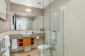 A modern bathroom with a glass shower enclosure, a sink with a vanity, and a toilet.
