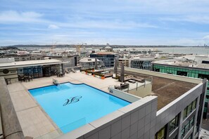 A rooftop pool with a view of the cityscape, including a hotel and construction cranes in the background. - Heritage Penthouse with Rooftop Pool & Balcony (Auckland)
