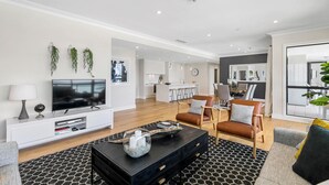 A modern living room with a flat-screen TV, a black coffee table, and leather sofas.