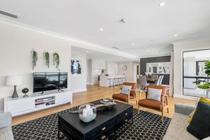 A modern living room with a flat-screen TV, a black coffee table, and leather sofas.
