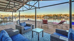A covered outdoor deck with wicker furniture, a small table, and a lounge chair. - Immaculate Waterfront Home for 16 w/ Private Dock! (Kingsland)