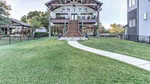 A two-story building with a central staircase, a covered outdoor seating area, and a fenced courtyard. - Immaculate Waterfront Home for 16 w/ Private Dock! (Kingsland)
