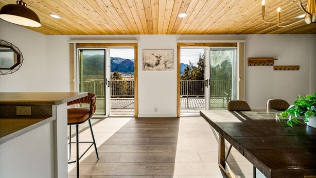 A modern kitchen with wooden ceiling, large windows, and a dining area with a view of mountains. - Newly Remodeled Mountain Cabin w/ Epic Views, A/C, Optional Hot tub, 2 Kitchens (Durango)