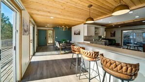 A modern kitchen with wooden ceiling, bar stools, and a dining area with a table and chairs. - Newly Remodeled Mountain Cabin w/ Epic Views, A/C, Optional Hot tub, 2 Kitchens (Durango)