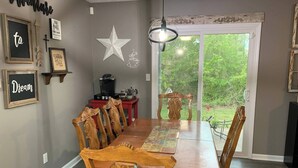 Une salle à manger avec une table et des chaises en bois, une machine à café et une décoration en forme d’étoile au mur.