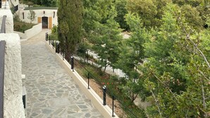 A stone pathway leading to a building with a door, surrounded by lush greenery and hills in the background. - Vacances à la mer apartments climatisés avec terrasse privative (Le Lavandou)
