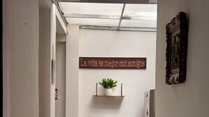 Ein Flur mit einem Schild, das 'La vida es mejor con amigos' zeigt, und einer Pflanze auf einem Regal.