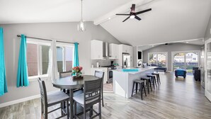 A spacious kitchen with a central island, a dining area with chairs, and a ceiling fan. - Charming 3-bedroom house on the Canal! Fireplace! Firepit! Pets Welcome! (Harrison Twsp)