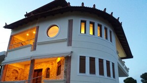 A two-story building with a stone facade, a balcony on the upper floor, and a circular window on the second floor. - Salty Sea Breeze nearby Athens airport (Artemis)