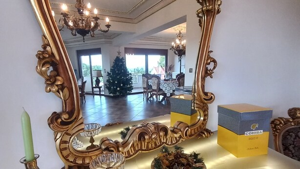 A room with a large ornate mirror, a Christmas tree, and a table with a box labeled "COHIBA." - Salty Sea Breeze nearby Athens airport (Artemis)