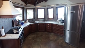 A modern kitchen with a curved layout, stainless steel appliances, and large windows. - Salty Sea Breeze nearby Athens airport (Artemis)