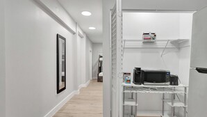 A hallway with a white door, a framed mirror, and a microwave on a metal shelf. - Miami Guest Suite with AC/WI-FI (North Miami Beach)