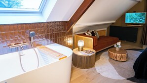 A modern bathroom with a freestanding bathtub, a shower, and a skylight.