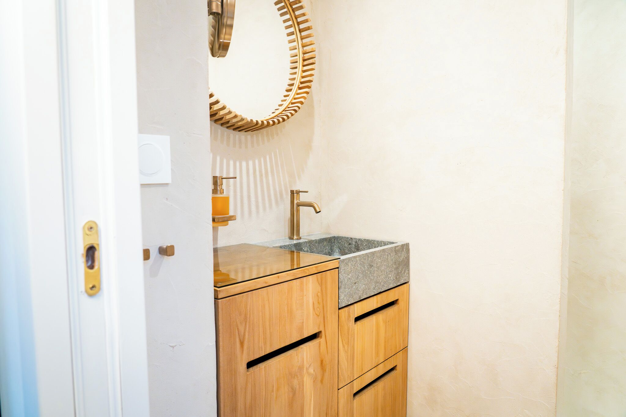 A bathroom with a wooden vanity, a sink, and a mirror with a unique frame.