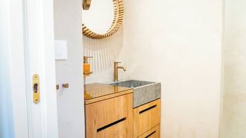 A bathroom with a wooden vanity, a sink, and a mirror with a unique frame.