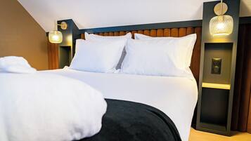 A hotel room with a large bed, two wall-mounted light fixtures, and a modern headboard.