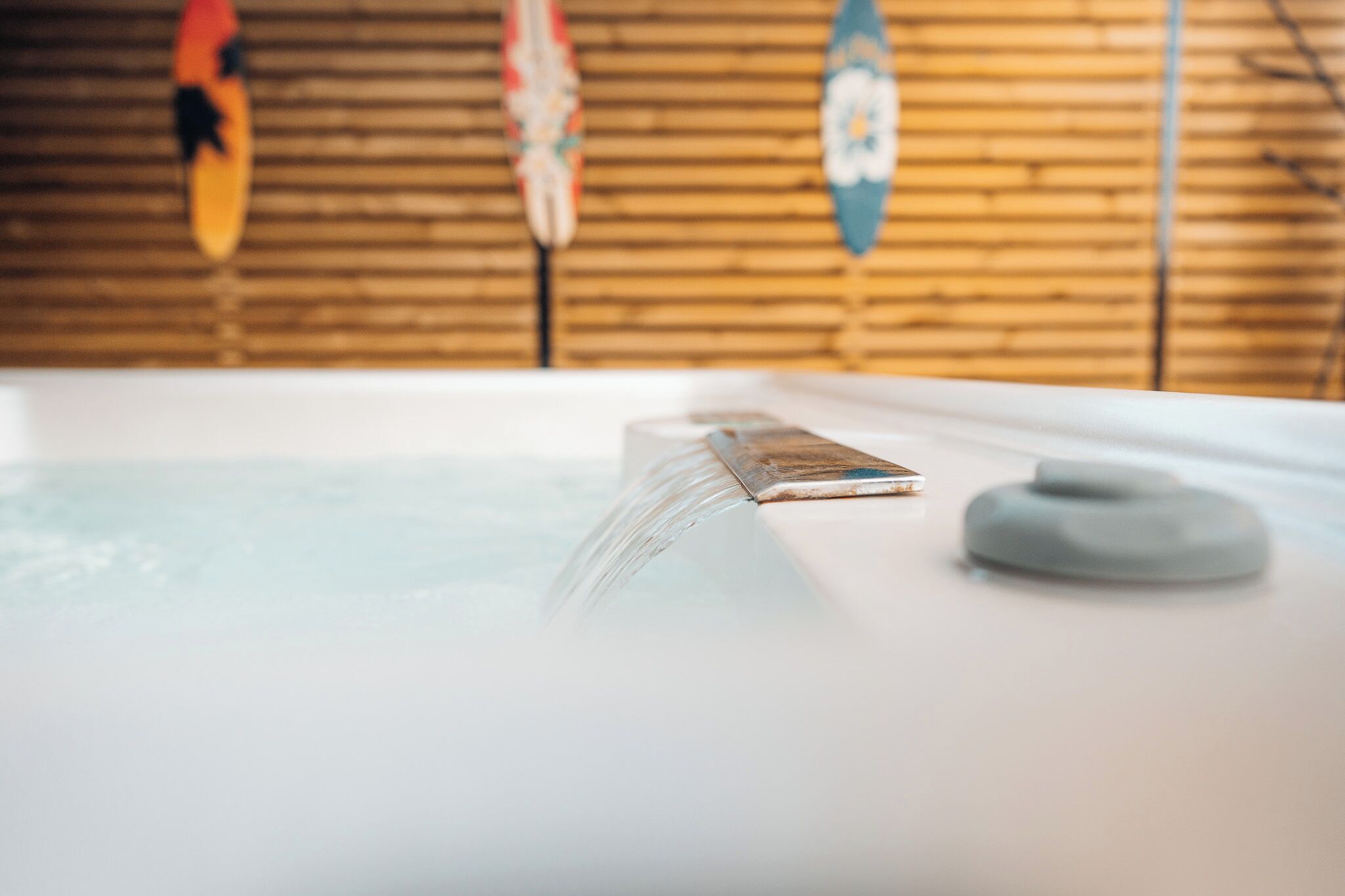A hot tub with a smartphone on the edge, surrounded by wooden walls and surfboards.