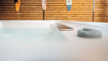 A hot tub with a smartphone on the edge, surrounded by wooden walls and surfboards.