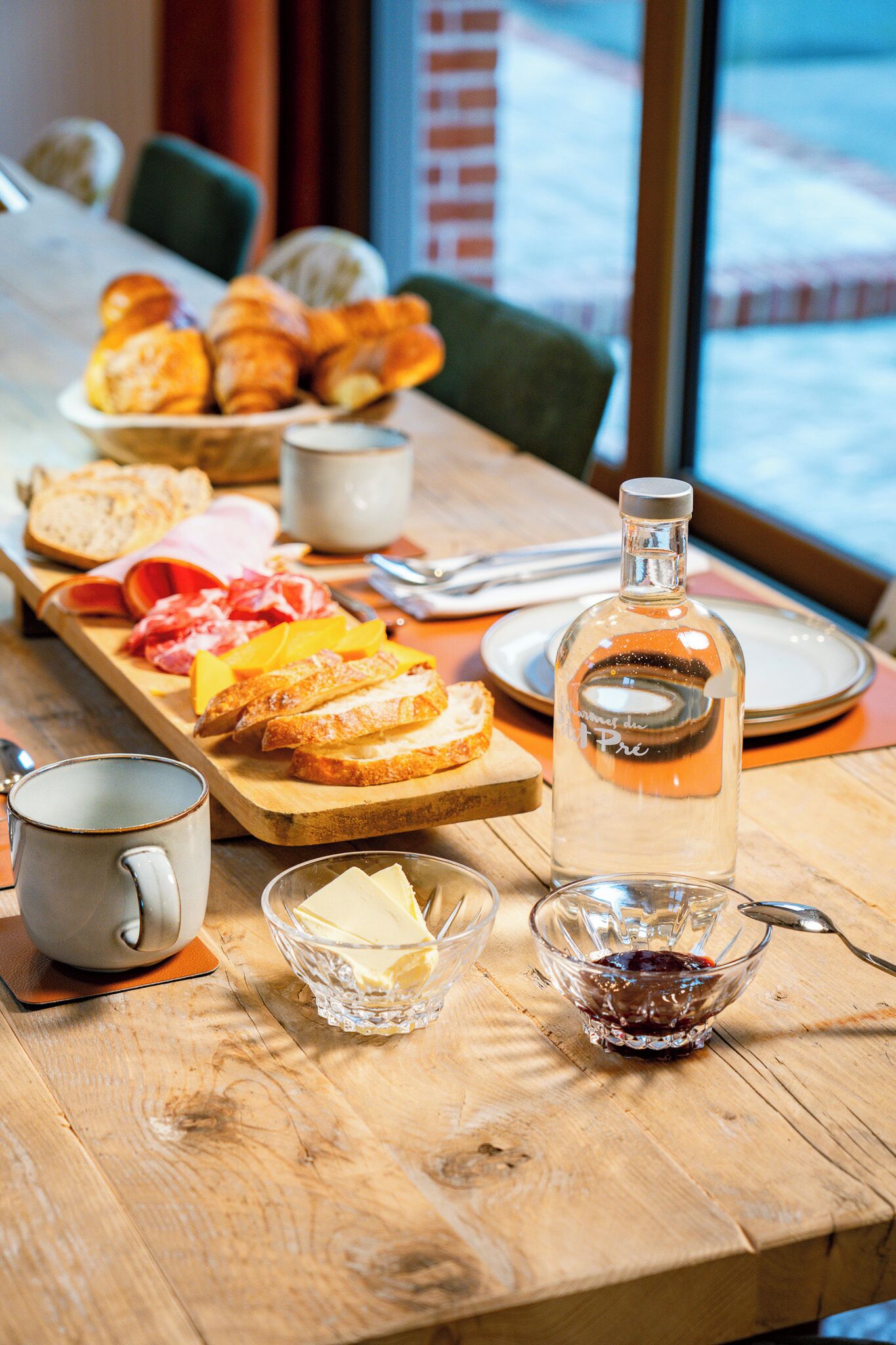A breakfast table with bread, cheese, and a bottle of water.