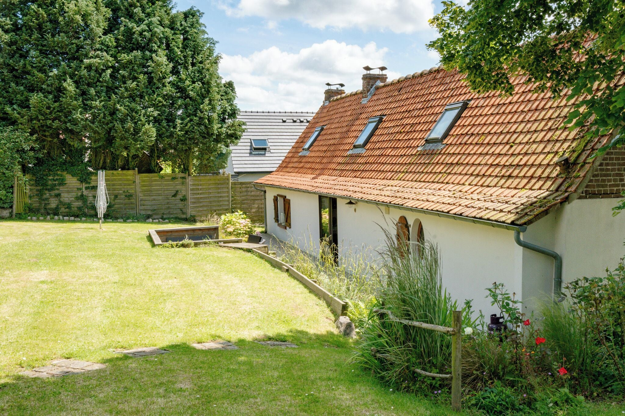 A house with a sloped roof, a small garden, and a wooden fence.