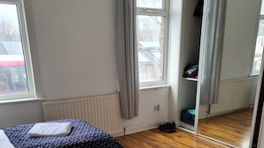A hotel room with two beds, a wooden floor, a radiator, and a wardrobe. - Cosy 4 bed house in great location. (London)