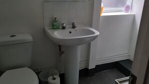 A small bathroom with a toilet, sink, and window. - Cosy 4 bed house in great location. (London)