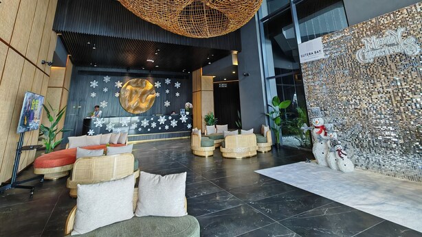 A modern lobby with a reception desk, seating area, and decorative elements like a large woven light fixture and a snowman decoration.
