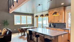 A modern kitchen with wooden cabinets, a large island, bar stools, and pendant lighting. - Paradise at Purg that sleeps 16 across from resort (Durango)