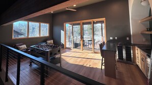 A spacious living area with a wooden ceiling, a foosball table, and a large sliding glass door leading to an outdoor patio. - Paradise at Purg that sleeps 16 across from resort (Durango)