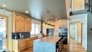 A modern kitchen with wooden cabinets, a large island, stainless steel appliances, and pendant lighting. - Paradise at Purg that sleeps 16 across from resort (Durango)