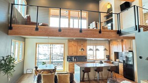 A spacious living area with a high ceiling, wooden beams, a mezzanine level, and a kitchen with modern appliances. - Paradise at Purg that sleeps 16 across from resort (Durango)