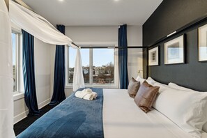 Ein modernes Hotelzimmer mit einem großen Bett, Blick auf die Stadt und einem Balkon.