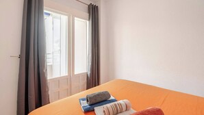 Hotellihuone, jossa on sänky, ikkuna verhoilla ja näkymä ulos.