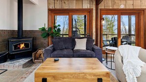 A cozy living room with a fireplace, a sofa, a coffee table, and a view of the outdoors. - Cozy 6-bedroom cabin in Wintergreen Resort (Wintergreen Resort)