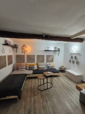 A cozy, well-lit room with a wooden floor, a sofa with patterned cushions, a small table, and wall-mounted decorations.