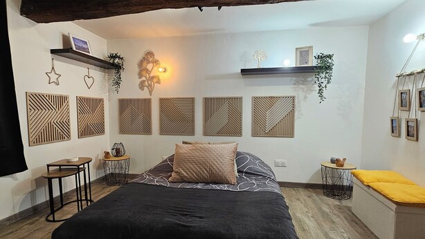 Ein Schlafzimmer mit einem großen Bett, Holzdielen und einer schrägen Decke mit freiliegenden Balken.