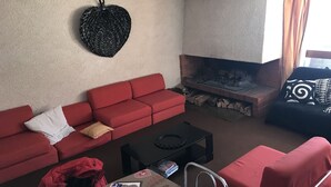 Una sala de estar con un sofá rojo, una mesa de centro negra, una chimenea y una lámpara colgante.