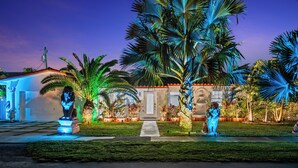 A house with a well-maintained lawn, palm trees, and a pathway leading to the entrance.