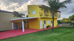 Een geel gebouw met een rood dak, een overdekte patio en een palmboom.