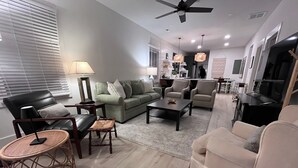 A modern living room with a sofa set, a coffee table, and a TV area.
