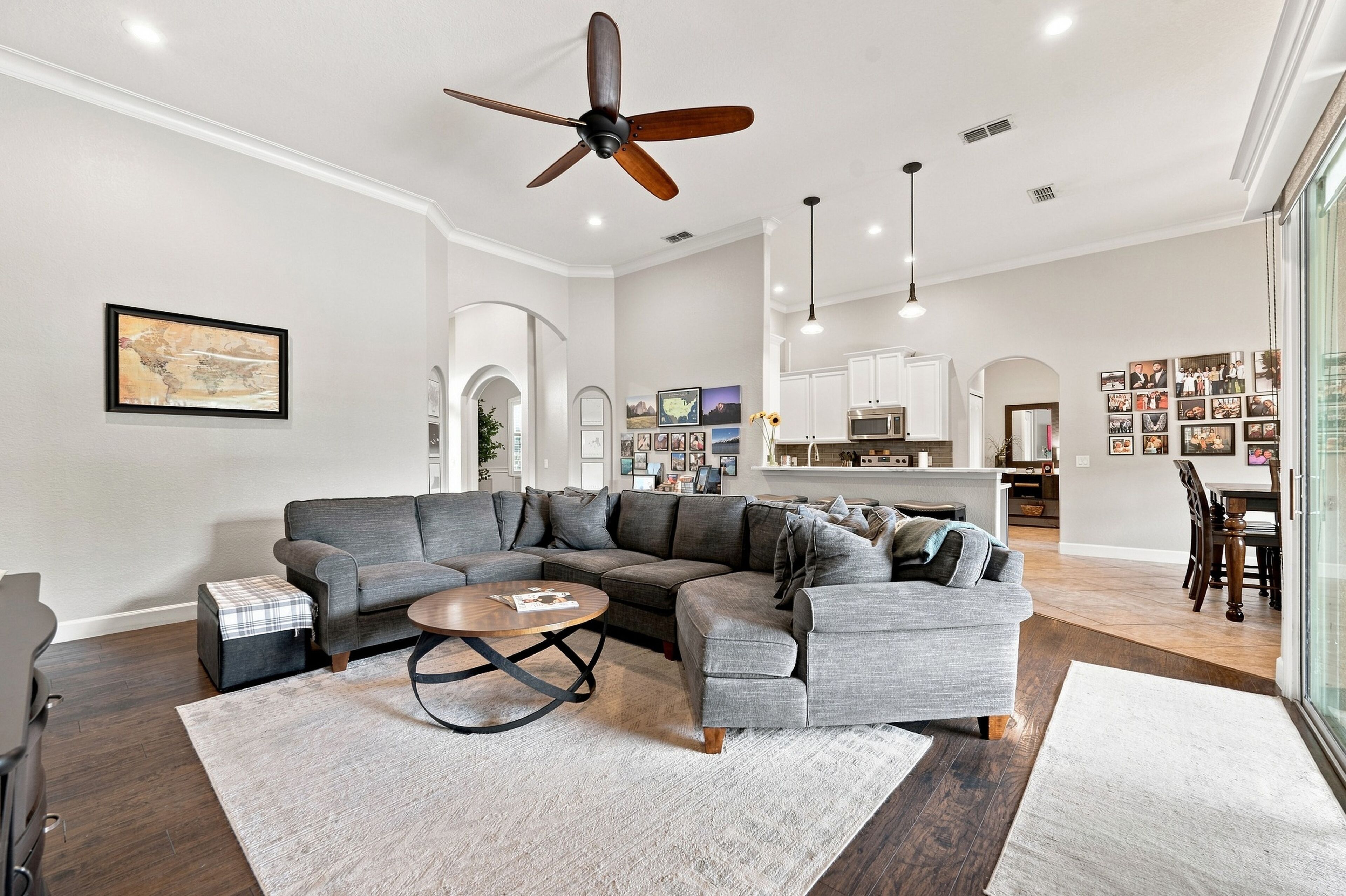 A spacious living room with a sectional sofa, a coffee table, and a ceiling fan.