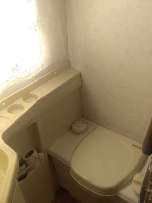 Ein kleines, kompaktes Badezimmer mit Toilette, Waschbecken und Fenster.
